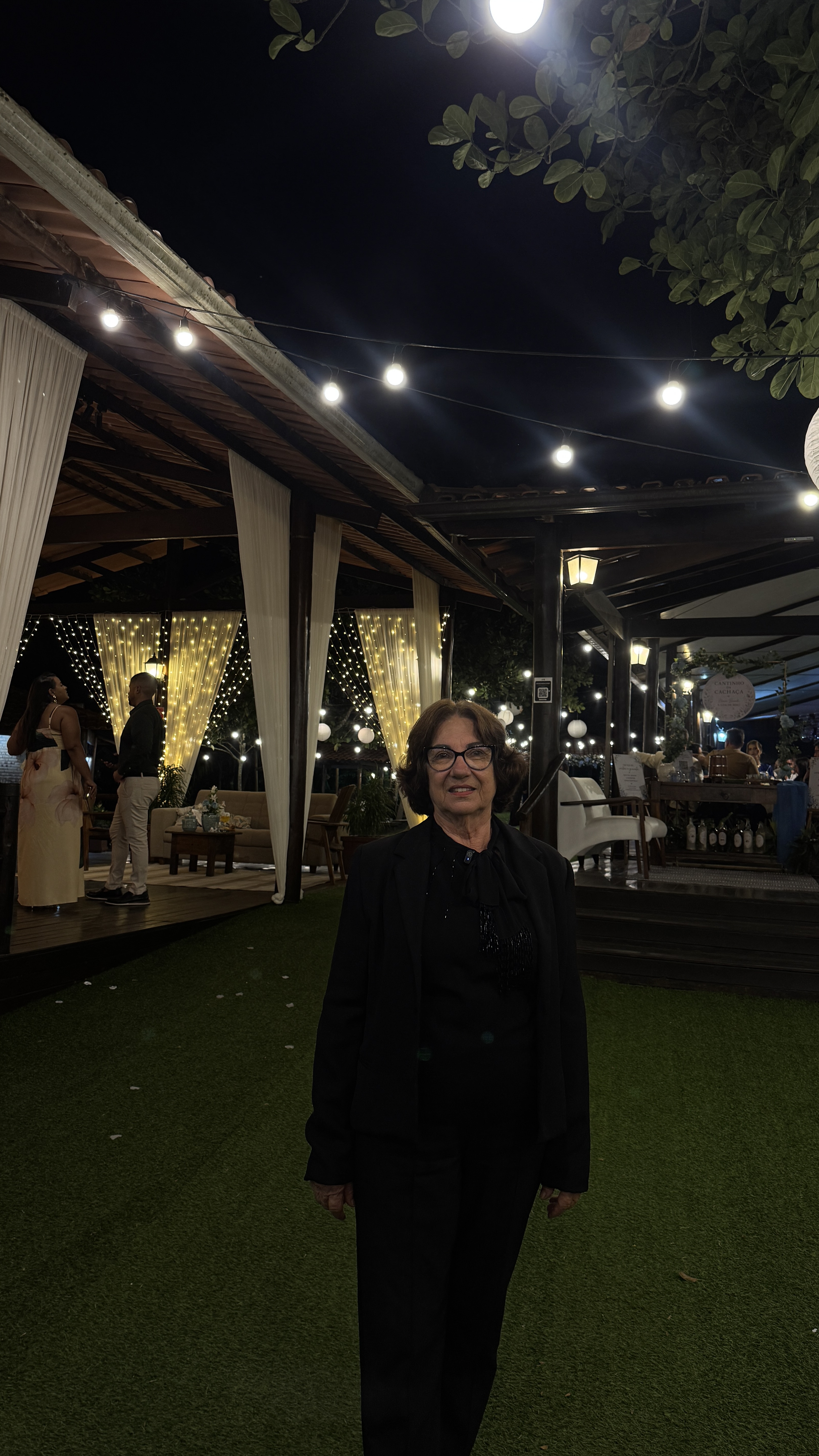 Dona Lúcia, a Nona Lú, no salão durante uma celebração à noite